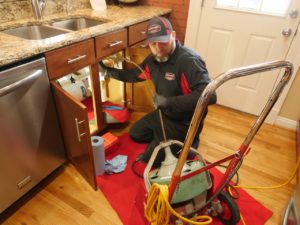 Technician performing plumbing maintenance in home